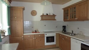 Una cocina con armarios de madera, un horno Bosch, lavavajillas y cafetera.