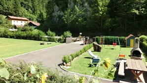 Un parque con juegos infantiles, mesas de picnic y zona de barbacoa.
