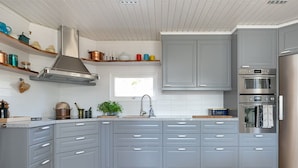 Una cocina moderna con armarios grises, una campana extractora de acero inoxidable y un horno doble.