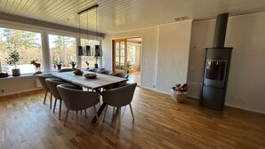 Un comedor moderno con una mesa y sillas de madera, ventanas amplias y un estufa de leña.