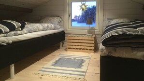 Een gezellige slaapkamer onder de dakpannen met twee bedden, een sterrenversiering op het raam en een houten vloer.