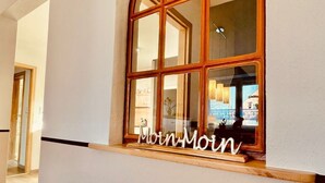 Un corridoio con una grande finestra ad arco, caratterizzata da una cornice in legno e una targa con su scritto 'Moin-Moin'.
