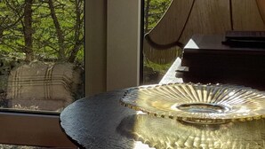 Een kamer met een groot raam, een houten stoel en een decoratief glazen object op een tafel.