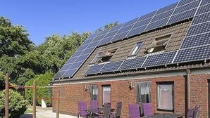 Un edificio con paneles solares en el techo y un patio con sillas y una mesa.