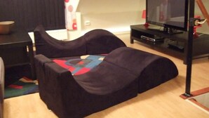 A room with a black sofa, a television on a black stand, and a small table with a bowl. - mit Blick auf das Wasser by Interhome (Helsingborg)