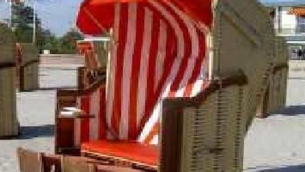 En strandstol med en stribet pude og et matchende parasol.
