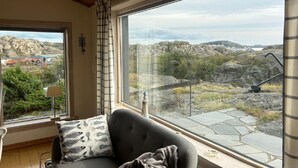 Et værelse med et stort vindue, der viser et stykke stenet landskab og fjerne bygninger.