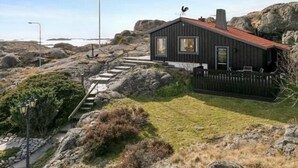Et kysthus med rødt tag, en lille terrasse og en indhegnet have.