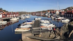 En lysthavn med flere både i havnen, træpromenader og bygninger med røde tage.