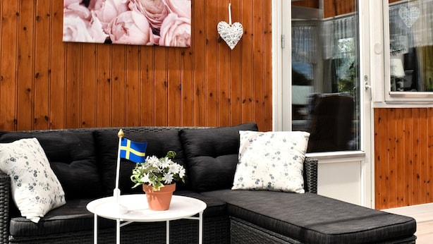 A modern living room with a black sofa, a small round table, and a potted plant with a Swedish flag. - Typisch schwedisches Ferienhaus mit Garten by Interhome (Vena)