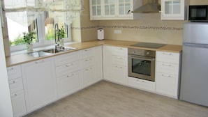 A kitchen with white cabinets, a stainless steel sink, a microwave, and an oven. - Barrierefreie FeHausHälfte mit Terrasse. by Interhome (Hasselberg)