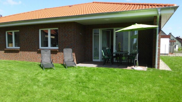 A house with a brick exterior, a tiled roof, and a covered patio area with two chairs and a table. - Barrierefreie FeHausHälfte mit Terrasse. by Interhome (Hasselberg)