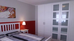 A bedroom with a bed, a nightstand, a lamp, and a wardrobe. - Barrierefreie FeHausHälfte mit Terrasse. by Interhome (Hasselberg)