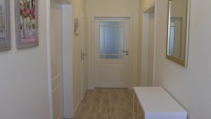 A narrow hallway with a white door at the end, a small white dresser, and two framed pictures on the walls. - Barrierefreie FeHausHälfte mit Terrasse. by Interhome (Hasselberg)