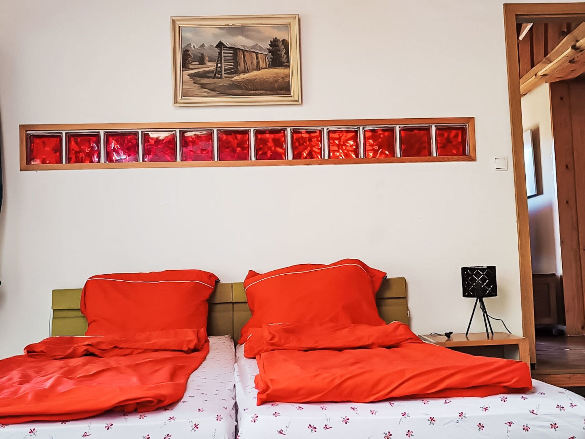A bedroom with two beds, a painting above the beds, and a red light strip on the wall.