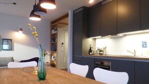 A modern kitchen with dark cabinets, a wooden dining table, and pendant lights. - Sonnendeck in Eckernförde by Interhome (Eckernförde)