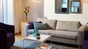 A living room with a grey sofa, a coffee table with a vase and a plant, a purple armchair, and a window with curtains. - Sonnendeck in Eckernförde by Interhome (Eckernförde)
