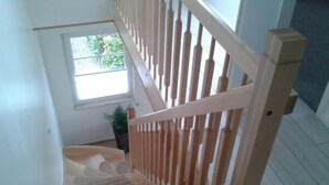 Eine Treppe mit Holzwertlauf und einem Blumentopf am Fuß.