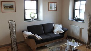 A living room with a sofa, a glass coffee table, and two windows with curtains. - Festung zu Ketghe by Interhome (Kettig)
