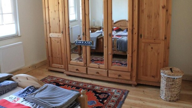 A bedroom with a wooden wardrobe, a bed, a small table, and a wicker trash bin. - Festung zu Ketghe by Interhome (Kettig)