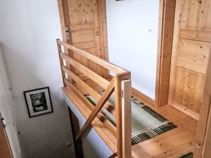 Een houten trap met een metalen leuning die leidt naar een kamer met een witte muur en een lijstwerk met een afbeelding.