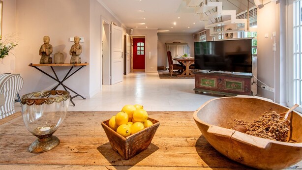 A spacious living room with a wooden floor, a dining area with a red door, and a kitchen with a large TV. - Horstweg in Westerland by Interhome (Archsum)