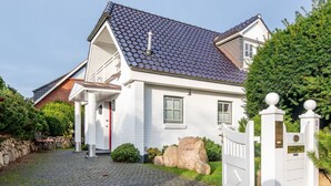 A white house with a tiled roof, a stone wall, and a cobblestone driveway. - Horstweg in Westerland by Interhome (Archsum)
