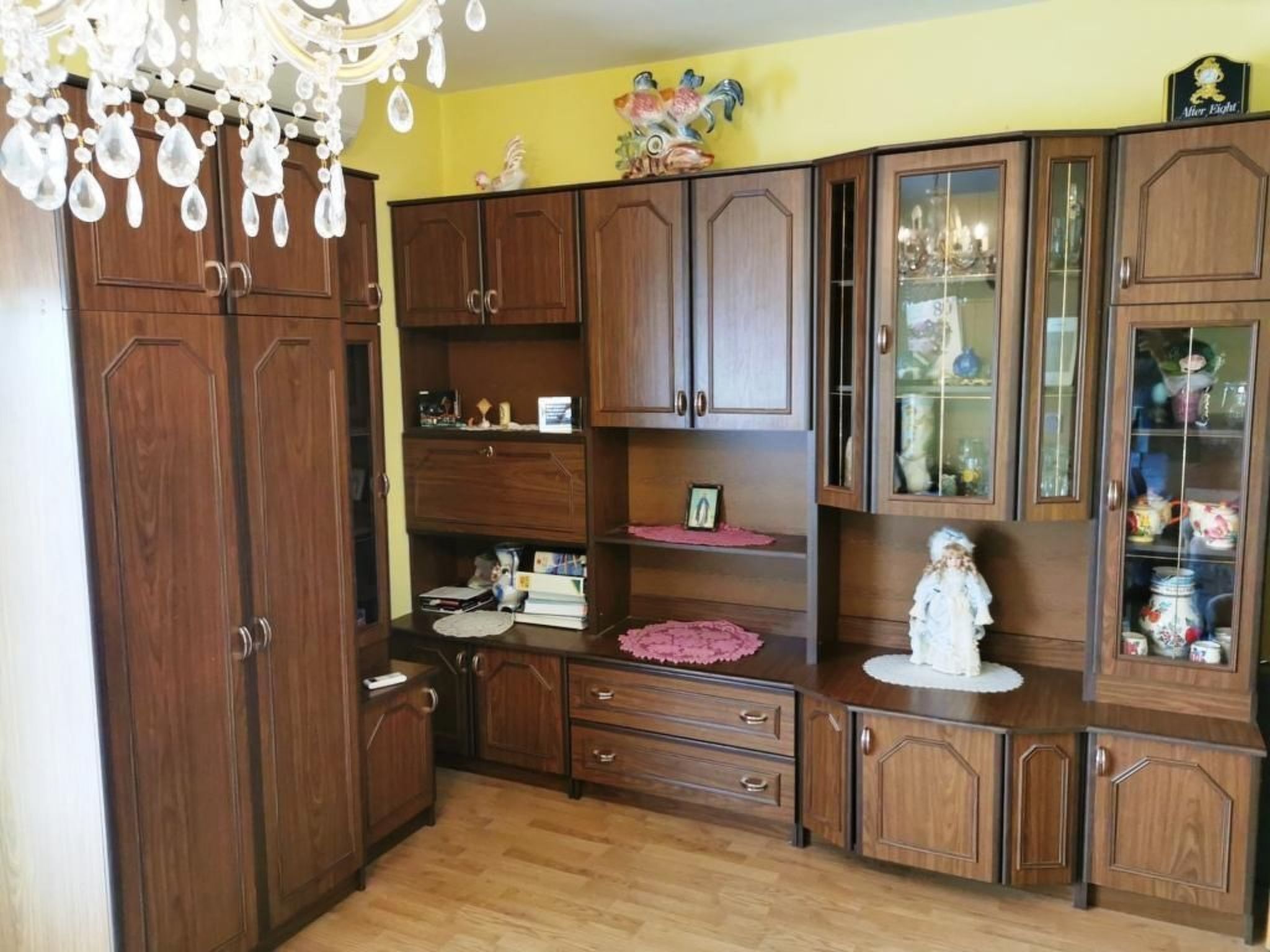 Una habitación con armarios de madera, una araña y varios objetos decorativos.