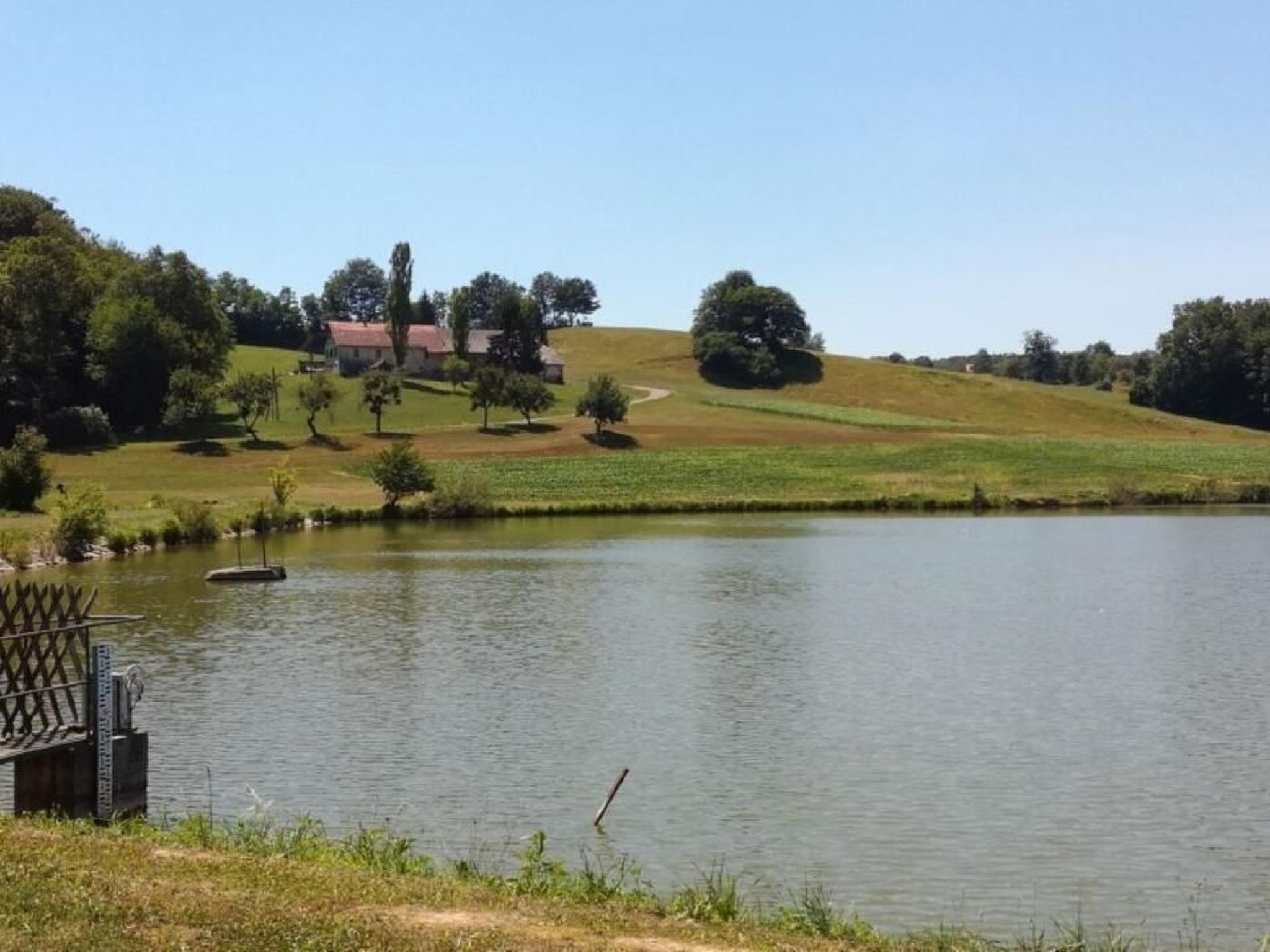 Eine friedliche Uferlandschaft mit einem kleinen Steg und einem Gebäude im Hintergrund.