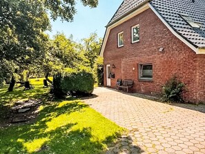 A brick building with a paved driveway, a bench, and a small garden area. - Ole School by Interhome (Nordstrand)