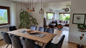 Ein Essbereich mit Holztisch und Stühlen, einer Pendelleuchte und Blick auf das Wohnzimmer.
