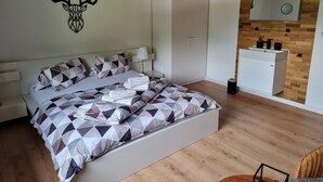 Ein modernes Schlafzimmer mit einem Bett, dessen Überwurf ein geometrisches Muster aufweist, einem aufgehängten Hirschgeweih an der Wand und einem Holzboden.