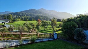 Ländliche Landschaft mit einem Haus, einem Holzzaun und einem Berg im Hintergrund.
