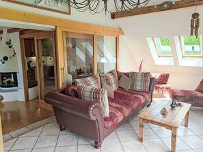 A cozy living room with a brown sofa, a wooden coffee table, and a view through a glass door to a kitchen. - Idyllische Panorama-Südwohnung in Wörtherseenähe by Interhome (Schiefling am See)