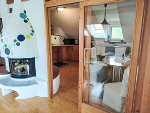 Ein gemütliches Interieur mit Kamin, Holzboden, Essbereich und Küche mit gefliestem Rücksprung.