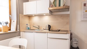 A compact kitchen with white cabinets, a sink, a kettle, and a compact dishwasher. - Apartment Grete by Interhome (Erfurt)