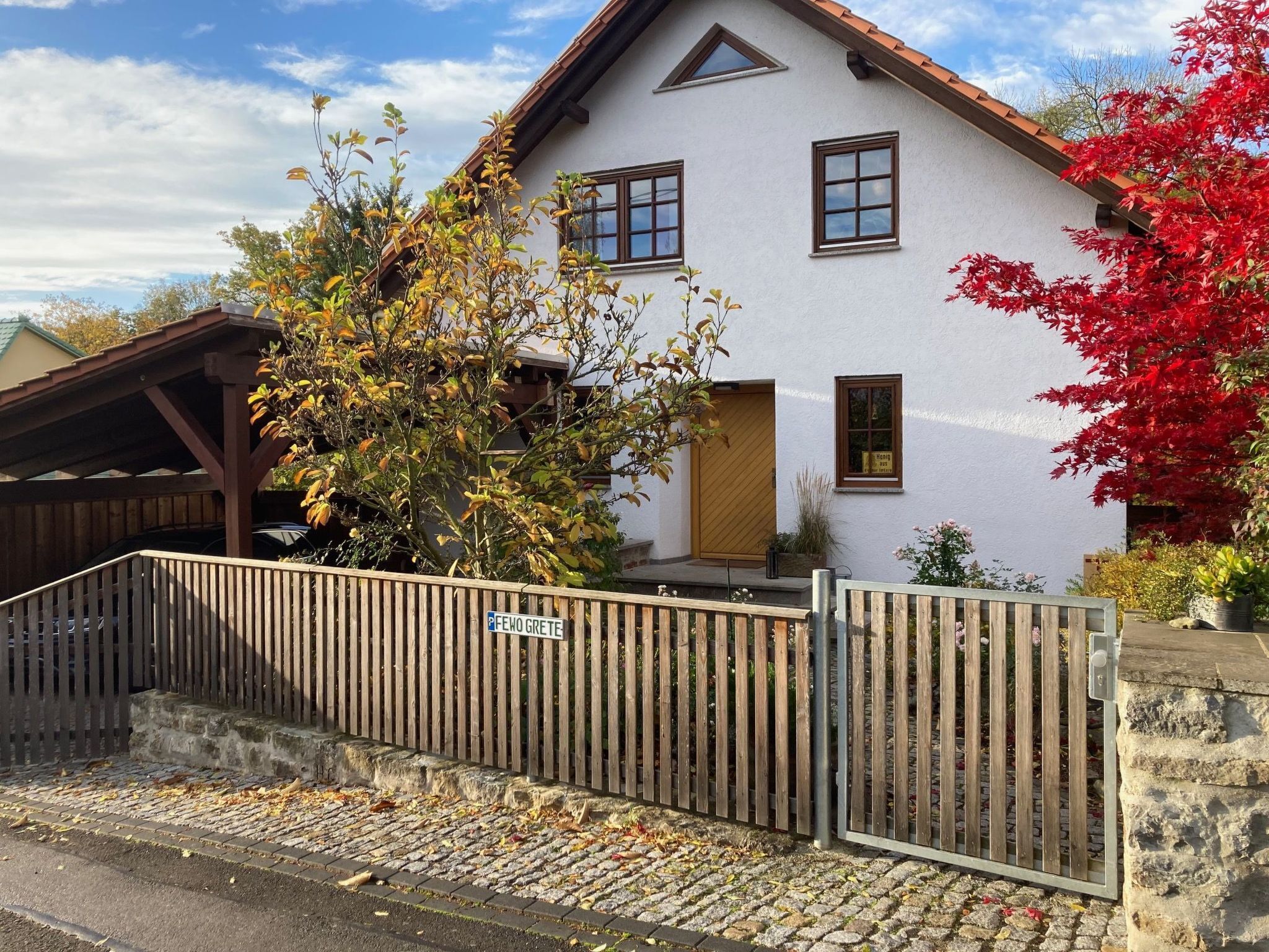 A white building with a sloped roof and a wooden fence in front.