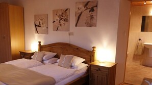 A bedroom with a wooden bed, two bedside tables, a fluffy rug, and three wall-mounted flower paintings. - Chalet Gove für Unterkunft mit Halbpension unter der Leitung des Eigentümers by Interhome (Tamsweg im Lungau)