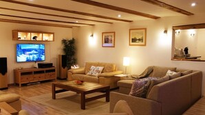 A cozy living room with a wooden ceiling, a television, a sofa, a coffee table, and a bookshelf. - Chalet Gove für Unterkunft mit Halbpension unter der Leitung des Eigentümers by Interhome (Tamsweg im Lungau)