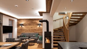 Ein modernes Wohnzimmer mit Kamin, Holzwänden, einer Couch und einem Essbereich.