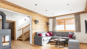 Ein modernes Wohnzimmer mit Holzbalkendecke, einer Sofagarnitur, einem Couchtisch und einem Kamin.