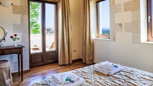 Habitación de hotel con cama, escritorio con espejo, florero con flores y vista al exterior.