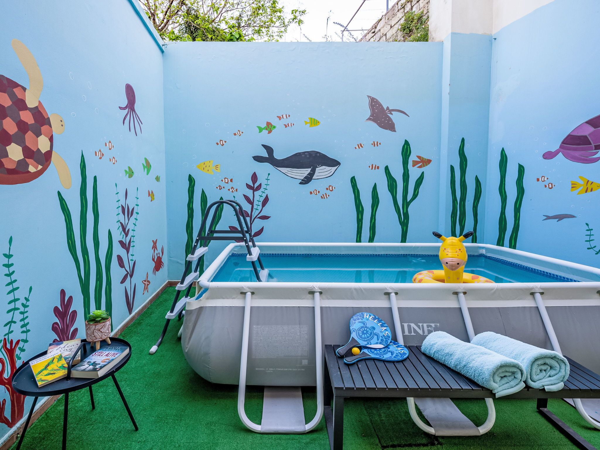 A pool area with a ladder, lounge chairs, and a pool table.