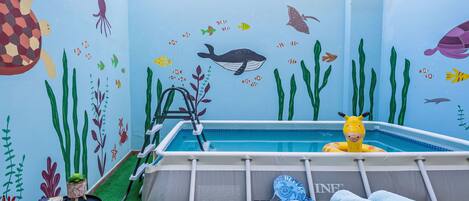 A pool area with a ladder, lounge chairs, and a pool table.