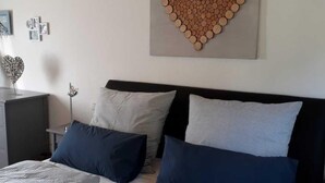 Camera da letto con un letto, due cuscini, un comodino e un elemento decorativo a parete.