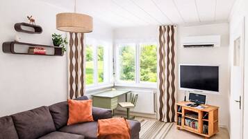 A modern living room with a sofa, a desk, a television, and a bookshelf.