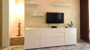 Ein Wohnzimmer mit einem an der Wand montierten Flachbildfernseher, einer weißen Unterhaltungseinheit darunter und einem gestreiften Boden.