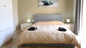 Ein Hotelzimmer mit einem Bett, zwei Nachttischen, einer Nachttischlampe, einem Gemälde an der Wand und einem gestreiften Boden.