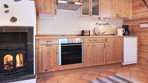 Una cocina con armarios de madera, estufa, cafetera y lavavajillas.