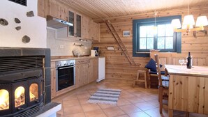 Una cocina acogedora de estilo cabaña con chimenea de piedra, armarios de madera y un comedor con mesa y sillas.